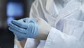 Hands of therapist taking off gloves after medical examination of patient