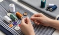 Hands Threading a Needle with Thread, Surrounded by Colorful Buttons and Spools Royalty Free Stock Photo