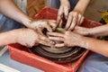 Hands of three people create pot, potter`s wheel. Teaching pottery