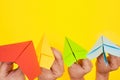 Hands throw paper planes multicolored on yellow background copy space one Royalty Free Stock Photo