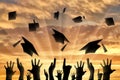 Hands throwing graduate cap in sky on sunset