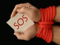 Hands tied with a rope, on a black background. Tied hands are holding a note with the inscription. Concept: loan, debt, help Royalty Free Stock Photo