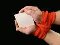 Hands tied with a rope, on a black background. Tied hands are holding a note with the inscription. Concept: loan, debt, help Royalty Free Stock Photo