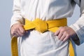 Hands tightening yellow belt on a teenage dressed Royalty Free Stock Photo