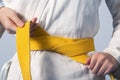 Hands tightening yellow belt on a teenage dressed Royalty Free Stock Photo