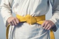 Hands tightening yellow belt on a teenage dressed in kimono Royalty Free Stock Photo