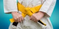 Hands tightening yellow belt on a teenage dressed in kimono for martial arts Royalty Free Stock Photo