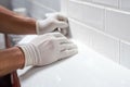 hands of the tiler are laying white ceramic tile on the wall. ai generated