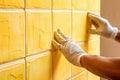hands of the tiler are laying yellow ceramic tile on the wall. ai generated