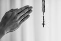 Man folded hands in prayer with rosary cross.