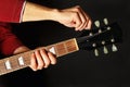 Hands tunes the electric guitar on dark background