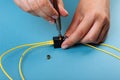 Hands tuning the Variable optic attenuator with a screwdriver. Selective focus. Blue background