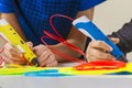 Kids hands with 3d printing pen and colorful filaments on white table Royalty Free Stock Photo