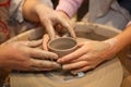 Hands of two people create pot on potter's wheel