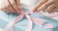 Hands tying pink ribbon on gift Royalty Free Stock Photo