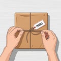 Hands tying string around a cardboard package labeled \