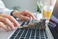 Hands type on a keyboard, while increasing coin stacks suggest financial development