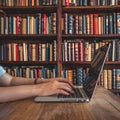 Hands type on laptop in cozy library setting