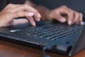 Hands typing on black laptop keyboard. Young man doing business or homework by searching, browsing information from internet.