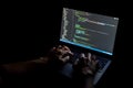 Hands typing code on a laptop screen in a dark room, programmer at work Royalty Free Stock Photo
