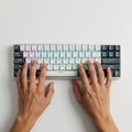 Hands typing on a compact mechanical keyboard with a white base and multicolored backlit keys. Royalty Free Stock Photo