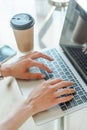 Hands typing on a computer keyboard over a white office table with a cup of coffee and supplies, top view. Royalty Free Stock Photo