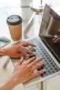 Hands typing on a computer keyboard over a white office table with a cup of coffee and supplies, top view. Royalty Free Stock Photo