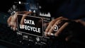 Hands Typing on Keyboard with Data Lifecycle Concept Overlay and Graphical Elements in a Dark Environment. Asymptotic Royalty Free Stock Photo