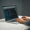 Hands typing on a laptop displaying a code editor with highlighted syntax in various colors. Royalty Free Stock Photo