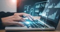Hands typing on a laptop displaying futuristic holographic data visualizations and charts in a modern office setting Royalty Free Stock Photo