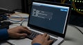Hands typing on laptop displaying network firewall rule configuration screen in dark server room Royalty Free Stock Photo