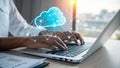 Hands typing on laptop with glowing cloud icon representing cloud computing and digital technology Royalty Free Stock Photo