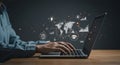 Hands typing on a laptop placed on a wooden desk. Digital icons, including graphs,