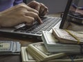 Hands are typing on laptop and stacks of money. Earnings on the Internet. Royalty Free Stock Photo