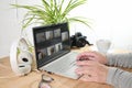 Hands typing on a laptop on a wooden desk with headphones, camera, coffee cup and plant, small office workplace for a creative Royalty Free Stock Photo