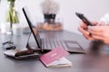 Hands typing on phone with a laptop, German passport and wallet in frame Royalty Free Stock Photo