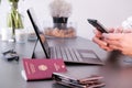 Hands typing on phone with a laptop, German passport and wallet in frame Royalty Free Stock Photo