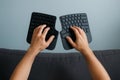 Hands typing on split ergonomic keyboard halves held separately against light blue background Royalty Free Stock Photo