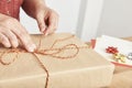 Hands of an unknown mature woman tying a Christmas gift with a decorative string Royalty Free Stock Photo