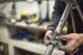 Hands of an unknown person sanding a bicycle frame at his workshop