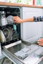 Hands of unrecognisable woman loading dishes into washing machine Royalty Free Stock Photo