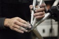 Hands of an unrecognizable hispanic man sanding a bicycle frame at his workshop