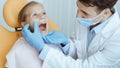 Hands of unrecognizable pediatric dentist making examination procedure for smiling cute little girl