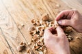 Hands of unrecognizable woman cracking walnuts, wooden table Royalty Free Stock Photo