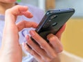 A hands of unrecognizable young caucasian woman is sitting at home-office tapping to smartphone`s screen. Royalty Free Stock Photo