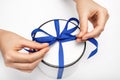 Hands untie the ribbon on the gift box. the girl opens a gift. gift round white box with a blue bow on a light background.