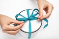 hands untie the ribbon on the gift box. the girl opens a gift. gift round white box with a blue bow on a light background.