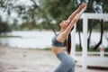 With hands up. Brunette with nice body shape in sportive clothes have fitness day on a beach