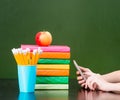 Hands used on the phone near books and green chalkboard. Sample for text Royalty Free Stock Photo