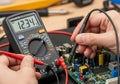 Hands using a digital multimeter to measure voltage on a circuit board. The multimeter display Royalty Free Stock Photo